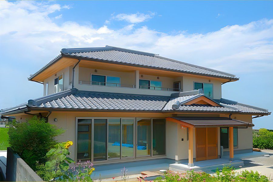 Nhà 2 tầng kiểu Nhật, hệ mái ngói sóng màu xanh đen xếp lớp cầu kỳ, tường sơn kem nhạt, cột gỗ và cửa trượt gỗ lớn