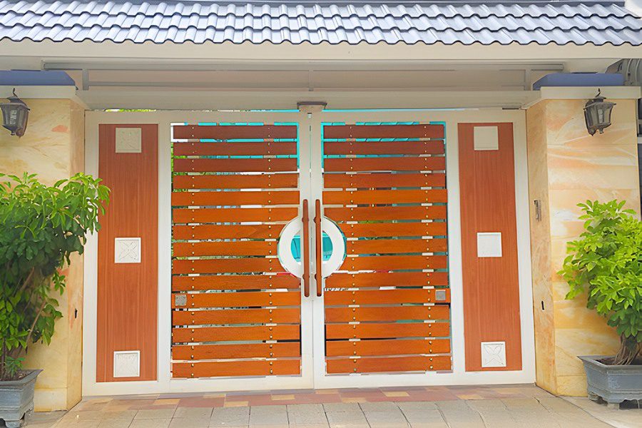 Cổng sắt giả gỗ 2 cánh màu trắng nâu có mái ngói xám hiện đại.